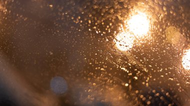 Yağmur damlaları ve ışıklarla bulanık arkaplan.