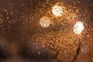 Yağmur damlaları ve ışıklarla bulanık arkaplan.