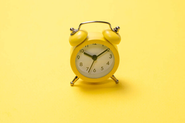 Yellow alarm clock on a yellow background.  Time concept. 