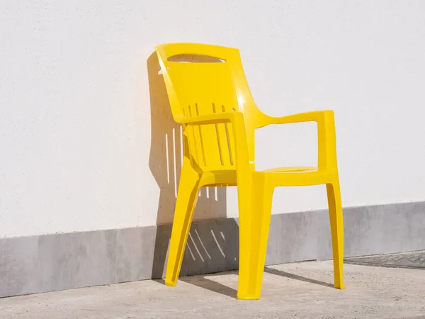 Żółte Plastikowe Krzesło Przy Szarej Ścianie Zewnątrz — Zdjęcie stockowe