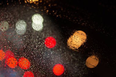 Yağmur damlaları ve ışıklarla bulanık arkaplan.