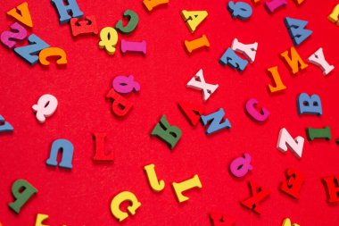 Kırmızı arkaplanda rastgele renkli alfabe, renkli harfler. Üst görünüm.