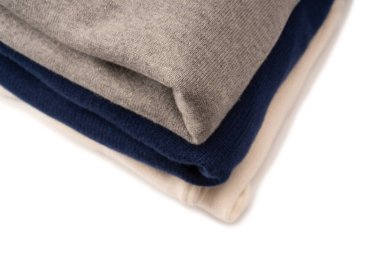 Beyaz arka planda izole edilmiş bir grup kalın kazak. Beyaz arkaplanda katlanmış süveter yığını.