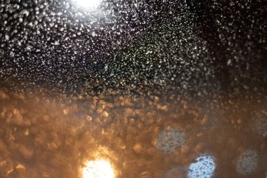 Yağmur damlaları ve ışıklarla bulanık arkaplan.