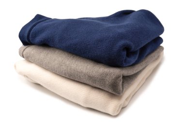 Beyaz arka planda izole edilmiş bir grup kalın kazak. Beyaz arkaplanda katlanmış süveter yığını.