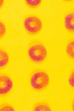Sarı arka planda jöleli şeker halkaları. Desen.