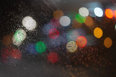 Yağmur damlaları ve ışıklarla bulanık arkaplan.