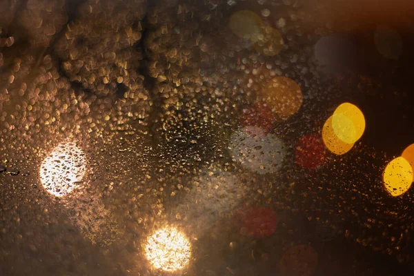 Yağmur damlaları ve ışıklarla bulanık arkaplan.