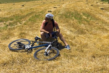 bisikletçi adam saman balya bir alanda üzerinde dinleniyor