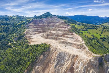 Çimento ocağındaki teraslar, şantiyede çalışan kamyonlar, hava manzarası.