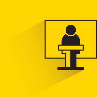 Kürsüde hoparlör ve sarı arkaplan arkasında beyaz tahta