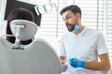 caucasian dentist talking with patient in clinic clipart