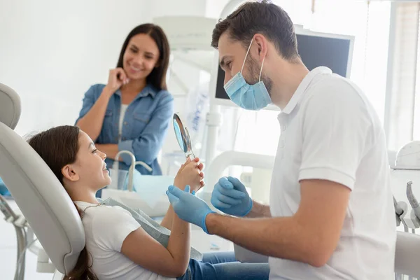 Retrato Menina Sorridente Olhando Espelho Após Procedimento Odontológico Enquanto Mãe — Fotografia de Stock