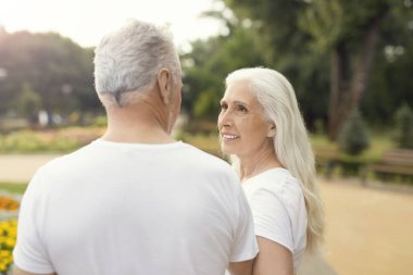 Parkta kocasına bakan uzun saçlı bir emekli.
