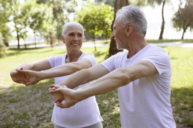 Mutlu yaşlı çift, kollarını temiz havada açarken birbirlerine sevgiyle bakıyor.