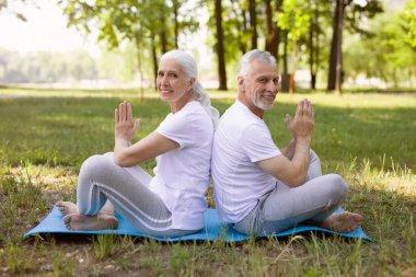 Nilüfer çiçekli mutlu çift yerde oturmuş meditasyon yapıyor.