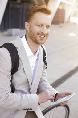 Memnuniyetle zarif bir adam elinde bir tablet tutuyor ve bakışlarını kaçırıyor.