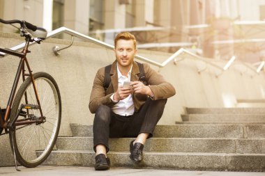 Akıllı telefonunu kullanan ve basamaklarda dinlenen hoş bir adam.