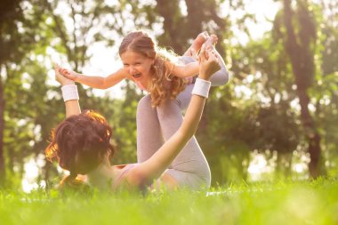 Parktaki çimenlerde uzanan ve sevgilisini havada bacaklarından tutan bir kadın.