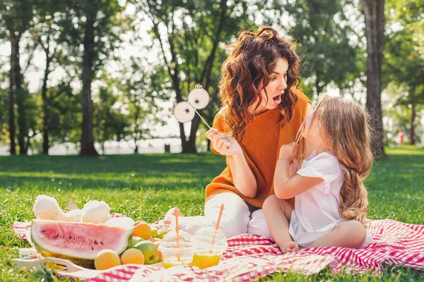 Mãe Olhando Para Sua Filha Segurando Máscaras Nos Paus Piquenique — Fotografia de Stock