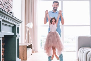 Baba 'nın kızını kucağına alıp evde el ele tutuşurken uzun bir çekim.