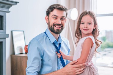 Babasına kravat bağlayıp evdeki kameraya bakan tatlı bir kız.