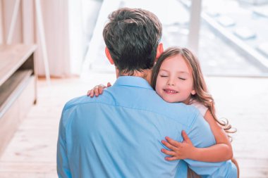 Kapalı gözlü küçük kızın portresi. Evde babasına sarılıyor.