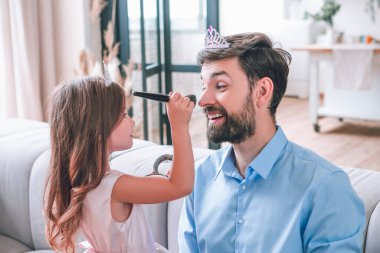 Evde babası için fırçayla makyaj yapan kızın portresi.