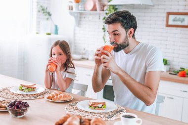 Baba ve kız sabah kahvaltıda meyve suyu içiyorlar.
