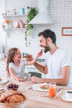 Baba ve kız birbirlerini ev mutfağında kurabiyelerle besliyorlar.