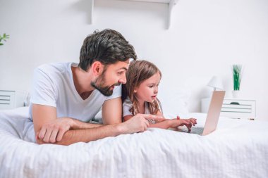 Kafkasyalı baba ve kızı evde dizüstü bilgisayar kullanıyor.