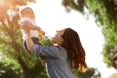 Anne parkta kucağında küçük bir çocuk tutuyor.