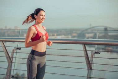 Sabah tek başına köprüde koşan bir yetişkinin yan görüntüsü.