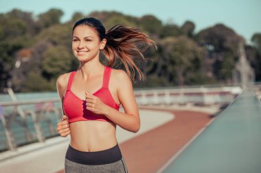 Mutlu bayan koşucu köprüde egzersiz yapıyor. Geçmişi bulanık.