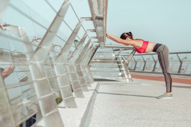 Genç bir kadın gündüz vakti şehir dışında ısınıyor.