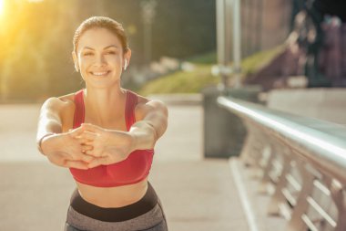 Kafkasyalı kadın elini uzatıyor ve dışarıda kameraya gülümsüyor.