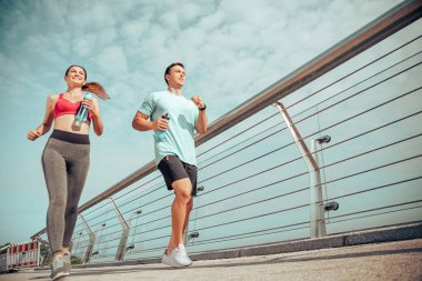 Şehir köprüsünde koşan iki kişinin düşük açılı görüntüsü