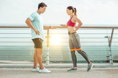 Köprüde lastik bant kullanan genç antrenör ve kadının yan görüntüsü