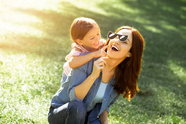 Sorridente Mãe Segurando Máscara Papel Com Filha Abraçando Pelas Costas — Fotografia de Stock