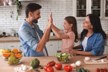 Anne onlara bakarken, baba ve kız mutfakta el ele oynuyorlar.