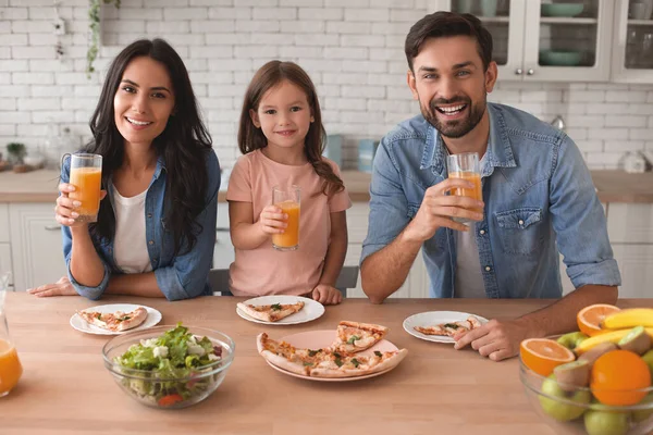 portrait of smiling family holding glasses with orange juice and looking at the camera