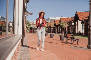 Şehirde yürürken akıllı telefon kullanan kadının tam boy görüntüsü.