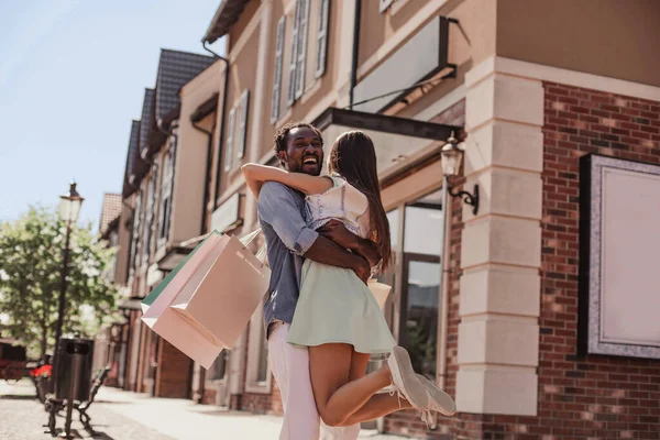 非洲裔美国男人 白天拿着购物袋牵着亚洲女人的手在街上走 — 图库照片