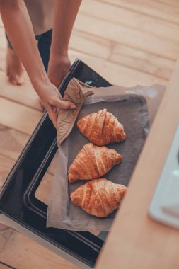 Kadın elleri fırından kruvasan çıkarıyor.