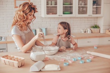 Küçük kız ve annesi mutfakta kurabiye için para kazanıyorlar.