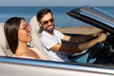 Gülümseyen kadına bakan mutlu adam Cabriolet 'te birlikte ata biniyor.