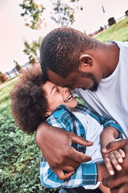 Dışarıda açık havada otururken baba ve çocuğunun kucaklaşması.