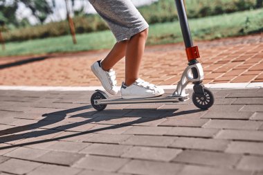 Kaldırımda scooter süren bir çocuğun kesilmiş fotoğrafı.