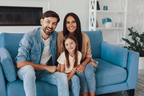 Gioiosa Bambina Seduta Divano Blu Tra Madre Amorevole Padre Premuroso — Foto Stock