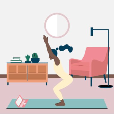 Genç siyahi bir kadın evinde internetten yoga yapıyor. Sandalyede duran kız Utkatasana 'ya poz veriyor. Karantina sırasında yoga egzersizleri. Çevrimiçi kurslar, dizüstü bilgisayar eğitimi.